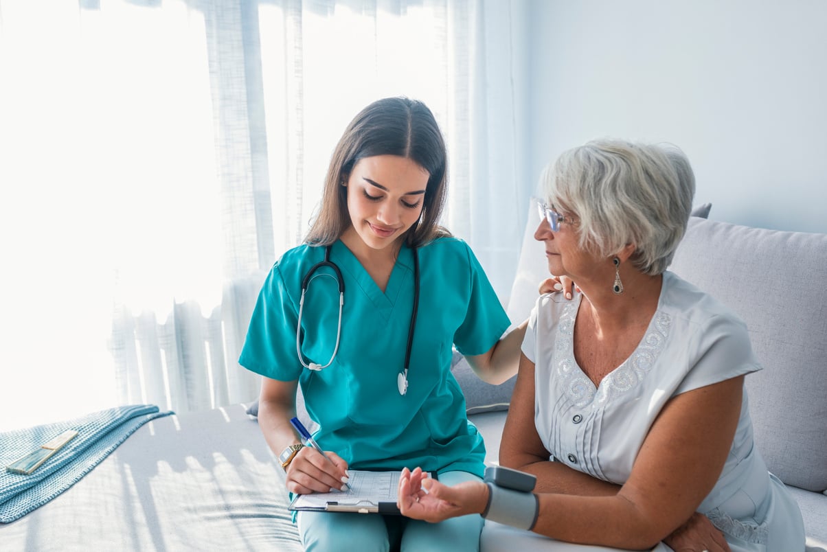 Nurse measuring blood pressure of senior woman at home